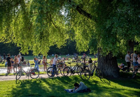 Large meadow at Schwabinger Bach, Many people on a summer day in the English Garden, Munich,