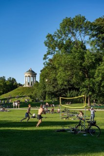 People playing volleyball in a meadow in the English Garden, people enjoying the summer day in the