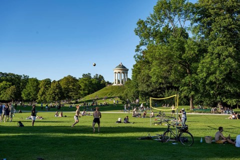 People playing volleyball in a meadow in the English Garden, people enjoying the summer day in the