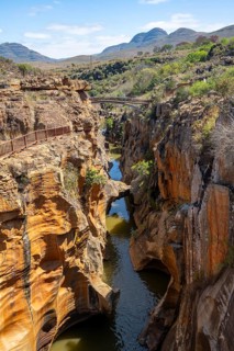 Bridge over a canyon with steep orange-coloured cliffs and the Blyde River, Bourke's Luck Potholes,