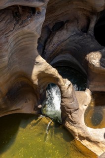 Water flowing through eroded rock formations, canyon with steep orange-coloured rock cliffs with