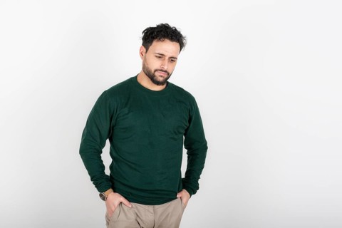Portrait of man with depressed attitude looking down and hands in pockets