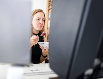 Food at work: A woman eats muesli with fruit in the office. Berlin, 25.07.2024