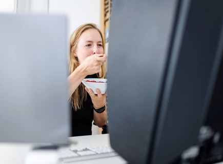 Food at work: A woman eats muesli with fruit in the office. Berlin, 25.07.2024