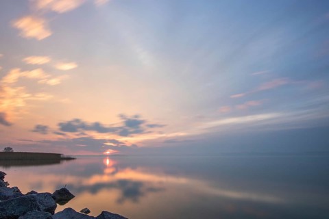Water landscape, taken from the shore of a calm lake. View over the reflecting water to the horizon