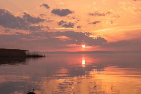 Water landscape, taken from the shore of a calm lake. View over the reflecting water to the horizon