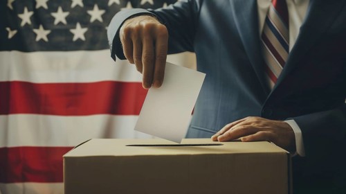 Man's hand in an elegant suit is putting a voting card into a voting box over the United States