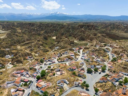 Panoramic view of a village embedded in a rocky and hilly landscape with mountains in the