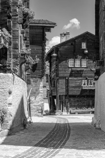 Paved footpath surrounded by old wooden houses, historic village centre, black and white