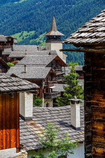 Old wooden houses with wooden shingle roofs in the historic centre of Grimentz, behind the church