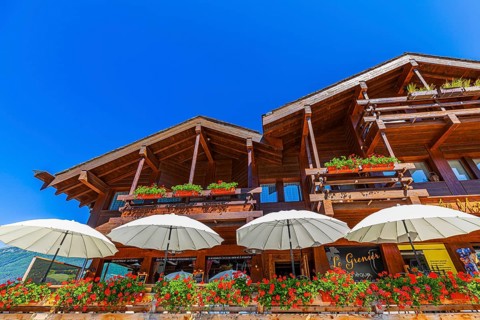 Modern chalet with terrace and white parasols, flower boxes in front of balconies, Grimentz, Val