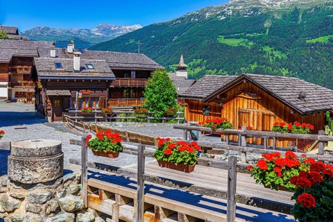 Old wooden houses with wooden shingle roofs and flower boxes in the historic centre of Grimentz,