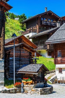 Old wooden houses with wooden shingle roofs and flower boxes in the historic centre of Grimentz,