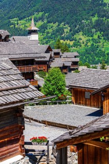 Old wooden houses with wooden shingle roofs in the historic centre of Grimentz, behind the church