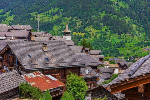 Old houses with wooden shingle roofs, Saint Theodule church at the back, historic village centre,
