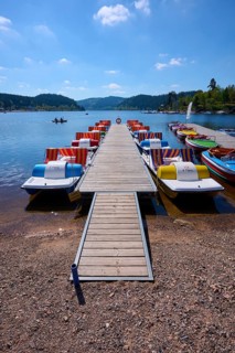 A picturesque scene with colourful pedal boats and wooden boats on a jetty in front of the