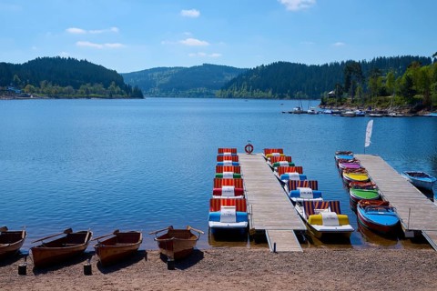 A picturesque scene with colourful pedal boats and wooden boats on a jetty in front of the