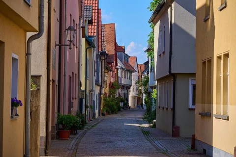 Idyllic narrow alley with cobblestones and traditional houses decorated with flowers under a bright