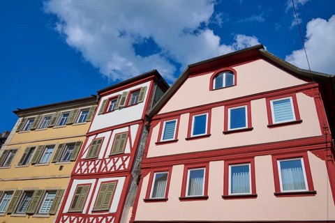 Three colourful half-timbered houses stand under a blue, cloudy sky, Karlstadt, Main Spessart,