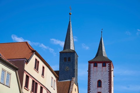 Two church towers and buildings in front of a blue sky in a cityscape, Karlstadt, Main Spessart,