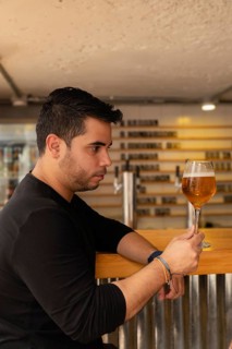 A Latino man in profile, looking appreciatively at his craft lager beer. The image captures his