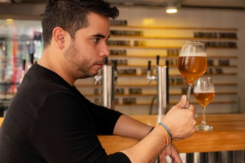 A Latino man savoring a craft lager beer, enjoying its rich flavor and quality. The image captures