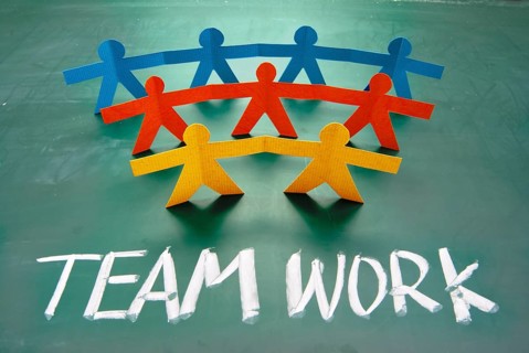 Teamwork words and colorful paper dolls on blackboard