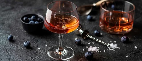 Elegant cocktail glass with a sophisticated drink and blueberries on a dark moody background, AI