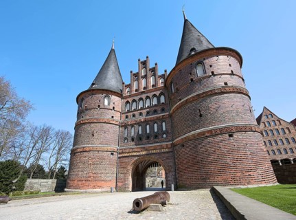 Lubeck Holstentor (Holsten gate) with canon, famous historic landmark with two round towers and an