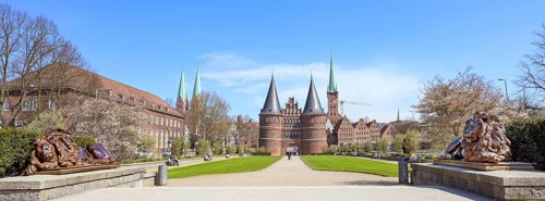 Wide panorama of the Lubeck Holstentor or Holsten gate park with two lion sculptures in front of