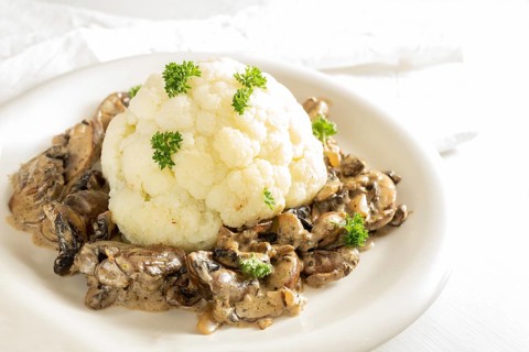 Cauliflower with mushroom ragout and parsley garnish, healthy vegetarian dish cooked from