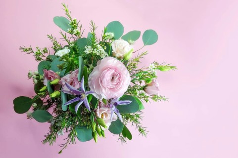 Flower bouquet from above against a pink background with copy space, feminine greeting card for