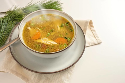 Hot steaming winter soup from chicken, vegetables and parsley in a bowl, home remedy against cold