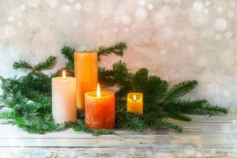 Third Advent, arrangement with four candles in orange and yellow, three are lit with a flame, fir