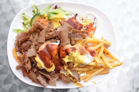 Doner kebab on a plate with French fries, salad and various sauces, popular fast food from Turkish