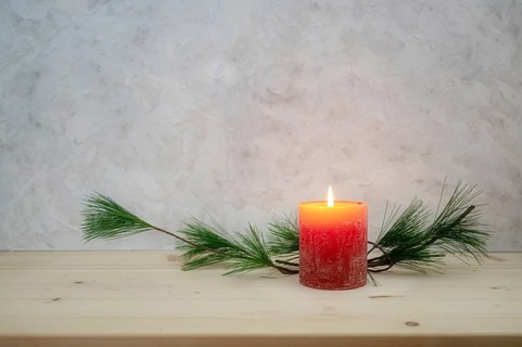 Red candle lit for the first Advent, pine branch as a simple, minimal decoration on a light wooden