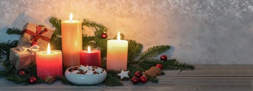 Advent candles in warm colors, cinnamon stars, Christmas decoration and fir branches on a rustic
