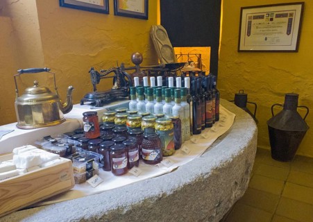 Display of products on a stone table surrounded by a yellow wall, including bottles and jars,