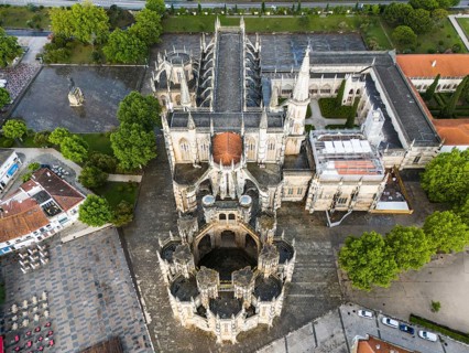Aerial view of a Gothic abbey with elaborate architecture surrounded by trees and squares, aerial