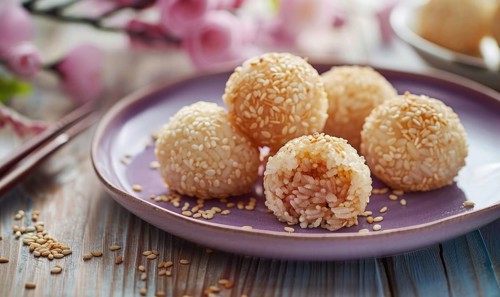 Sweet rice dumplings with sesame filling on a pastel purple plate AI generated