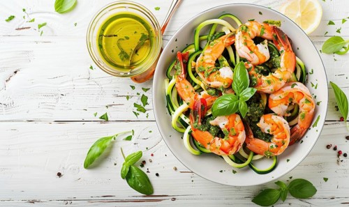 Shrimp and zucchini noodles with pesto on a light wooden background AI generated