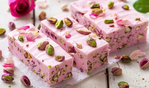 Rose and pistachio nougat on a light wooden background AI generated