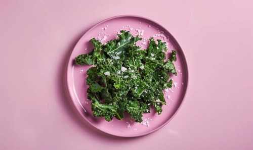 Kale chips with sea salt on a pastel purple plate AI generated