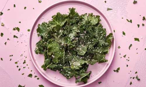 Kale chips with sea salt on a pastel purple plate AI generated