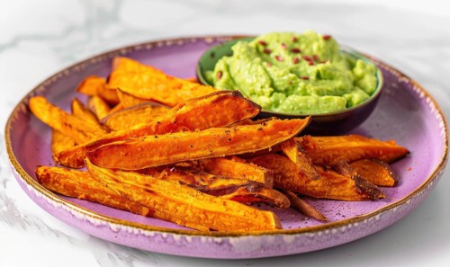 Baked sweet potato fries with avocado dip on a pastel purple plate AI generated