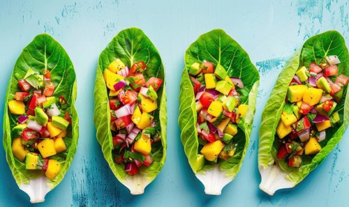 Avocado and mango salsa on endive leaves on a light blue background AI generated