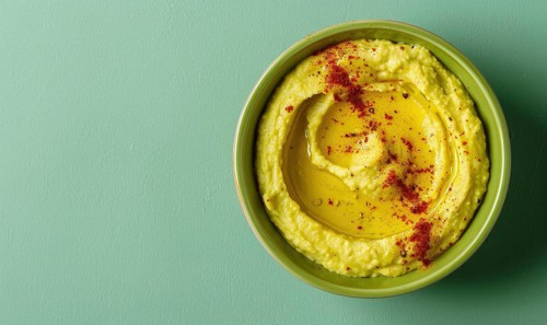 Avocado and hummus dip on a light green background AI generated