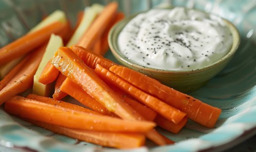 Avocado and carrot sticks with yogurt dip on a pastel green plate AI generated