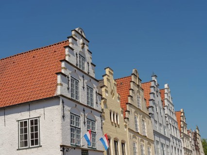 Historic houses with Dutch flags and distinctive gables under a blue sky, friedrichstadt,