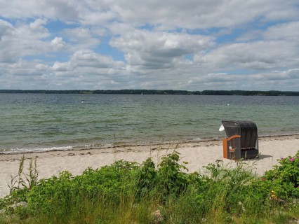 A beach with a lonely beach chair and a view of the sea under a cloudy sky, Glücksburg,
